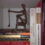 A statue of a man holding a cane on top of books.